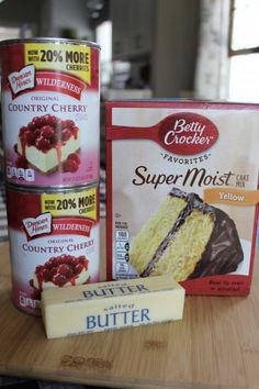 three cans of cake mix next to each other on a wooden table with two pieces of cake in front of them