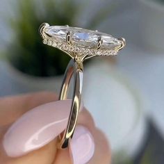 a close up of a person's hand holding an engagement ring