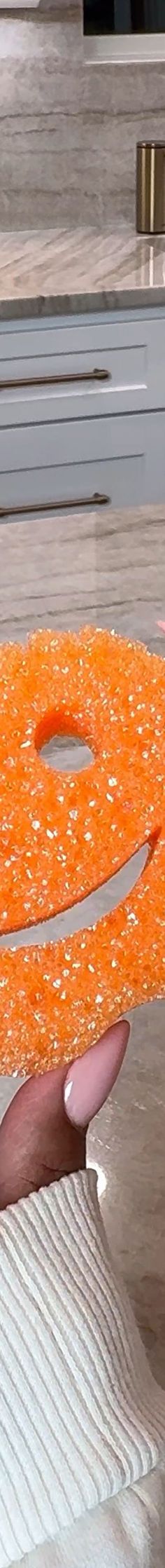 an orange object being held by someone's hand in front of a conveyor belt