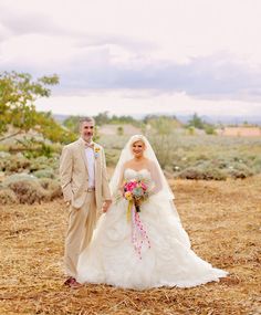 a bride and groom standing in the middle of a field