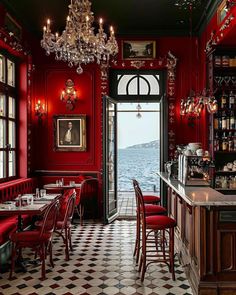 a restaurant with red walls and black and white checkered flooring, chandeliers hanging from the ceiling