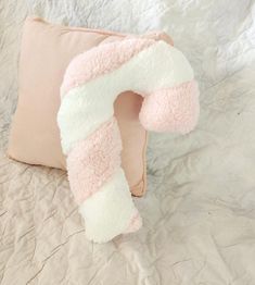 a pink and white pillow on top of a bed next to a beige pillow case