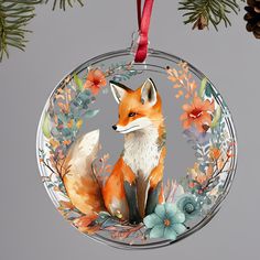 a glass ornament with an orange fox and blue flowers on it's side