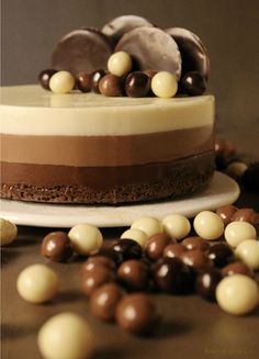 a chocolate cake with white and brown toppings on a plate next to some candies