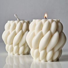 two white candles sitting next to each other