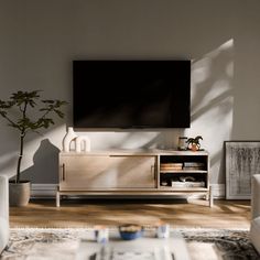 a living room with white furniture and a large flat screen tv mounted on the wall