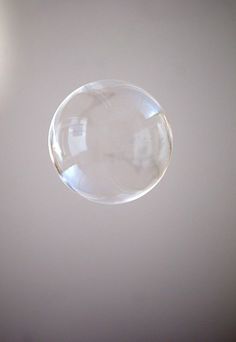 a clear bubble floating in the air on a white surface with light shining through it