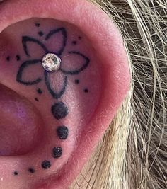 a close up of a person's ear with a flower tattoo on it