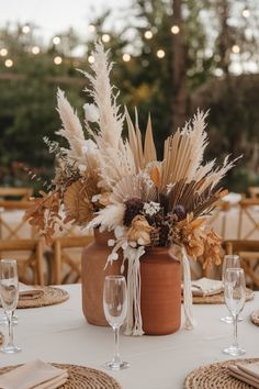 Pampas grass and dried flower boho wedding centerpiece in earthy tones on a rustic table. Spring Boho Wedding Centerpieces, Boho Chic Wedding Reception Decor, Pampas Wedding Arch Ideas, Wedding Table Centerpieces Dried Flowers, Simple Boho Wedding Table Setting, Boho Pampas Grass Bouquet, Rustic May Wedding, Outdoor Wedding Reception Centerpieces, Boho Table Flower Arrangements