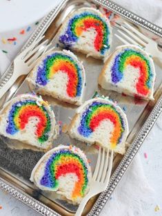 four rainbow cake bites on a silver tray with a fork and sprinkles