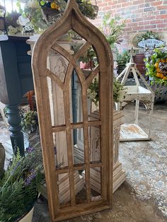 an old window is sitting on the ground in front of some potted plants and flowers