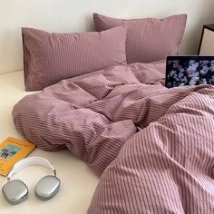 a laptop computer sitting on top of a bed next to headphones