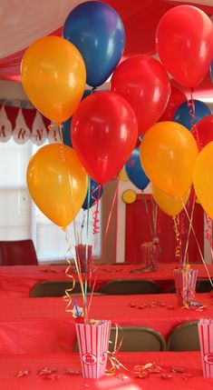 there are many balloons in the air on this red table clothed tablecloths