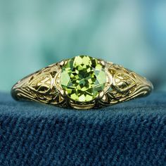 Step into a world of timeless elegance with our stunning vintage-inspired ring. Crafted with care, this ring features a carved yellow gold band that exudes luxury and sophistication. At its heart lies a mesmerizing lime green faceted cut-round peridot gemstone, radiating with vibrant beauty and charm. CHARACTERISTICS Status: Made to order Origin: Thailand Metal: Solid 9K Yellow Gold Ring Size: US 3-8 Total Gemstones Weight: 1.00 carat. (approx.) Total Gram Weight: 2.20 g. (approx.) *Pictures hav Heirloom Yellow Gold Emerald Ring With Center Stone, Heirloom Emerald Ring In Yellow Gold With Diamond Cut, Green Heirloom Filigree Ring For Formal Occasions, Heirloom Green Filigree Ring For Formal Occasions, Classic Gold Filigree Ring With Center Stone, Heirloom 14k Gold Filigree Ring For Anniversary, Elegant Engraved Yellow Gold Birthstone Ring, Heirloom Gold Emerald Ring With Diamond Cut, Victorian Yellow Gold Emerald Ring For Anniversary