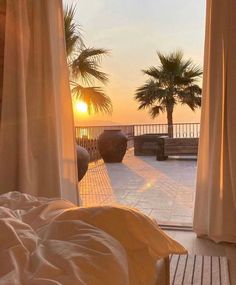 an open door leading to the beach at sunset with palm trees in the foreground