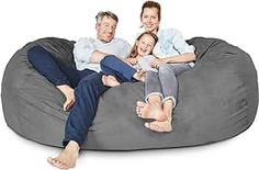 three adults and two children sitting on a large bean bag chair with the legs extended