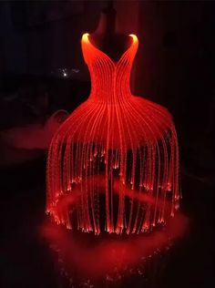 a large red sculpture is lit up in the dark with lights on it's sides