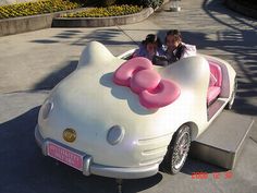 a hello kitty car is parked on the side of the road with people in it