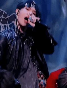 a male in a black leather jacket singing into a microphone