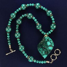 This is part of Chairish’s Costume Jewelry assortment.  22 Inch necklace of fabulous malachite in 16MM and 6MM smooth rounds with gold tone flutters.  The free form malachite pendant is 2.25 x 1.50 inches. The 22 inch necklace is secured with a gold-plate two ring toggle clasp. Elegant Green Turquoise Necklace In Chrysocolla, Elegant Green Chrysocolla Turquoise Necklace, Elegant Green Turquoise Chrysocolla Necklace, Elegant Turquoise Chrysocolla Necklace, Green Chrysocolla Single Strand Necklace, Turquoise Malachite Beaded Jewelry, Elegant Green Chrysocolla Jewelry, Elegant Chrysocolla Cabochon Necklace, Green Chrysocolla Necklace With Large Pendant