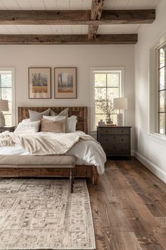 a bed sitting in a bedroom on top of a wooden floor next to two windows