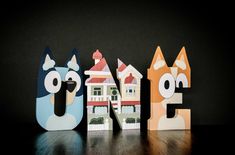 three wooden letters that spell out the word home with cats and dogs in front of them