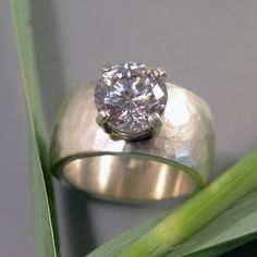 a diamond ring sitting on top of a green plant