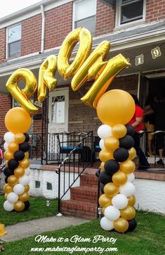 some gold and black balloons are in front of a house