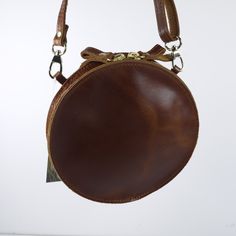 Embossed Leather Shoulder Round Bag Handmade Cross Body Saddle Vintage Handbag Height: 6.9 inches (15.5 cm) Width: 6.9 inches (15.5 cm) Depth: 1.4 inches (3.5 cm) Strap Length: max 56 inches (143 cm) This is a Handmade Cross-body Bag in Brown, Natural Tan and Black color. It has one compartment and secures with a zipper. The strap is removable and adjustable for your shoulder. Natural vegetable tanned leather will age and darken with the sun just like your own skin. Sun exposure and daily handli Brown Round Case Bag With Detachable Strap, Brown Satchel With Removable Pouch And Round Handle, Brown Crossbody Shoulder Bag With Brass Hardware, Brown Shoulder Bag With Round Handle, Brown Shoulder Bag With Round Handle For Everyday, Brown Saddle Shoulder Bag With Brass Hardware, Brown Shoulder Bag With Adjustable Strap And Round Handle, Brown Shoulder Bag With Leather Lining And Round Handle, Brown Round Case Shoulder Bag For Travel