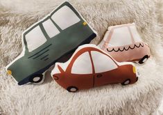 two pillows with cars on them sitting on a white furnishing area next to each other