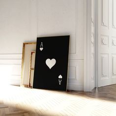 two playing cards sitting on the floor next to an empty frame with hearts and spades