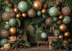 a jungle themed backdrop with leopard print balloons and green, gold and brown balls on the wall