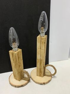 two wooden candlesticks with clear glass holders on wood slices and roped ends