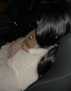 a woman holding a baby wrapped in a blanket while sitting in the back seat of a car