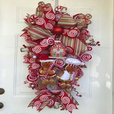 a christmas wreath with gingerbreads, candy canes and other decorations hanging on the front door