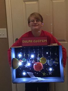 a boy holding up a solar system display