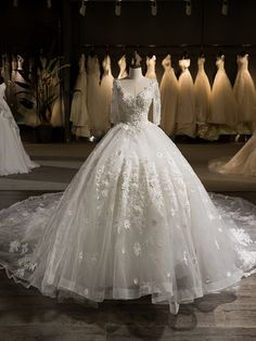 a white wedding dress is on display in a room with other dresses and gowns