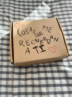 a cardboard box with writing on it sitting on a checkered tablecloth covered bed