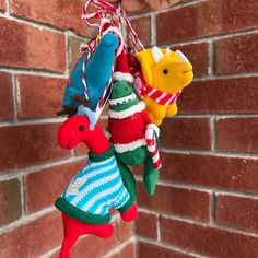 a hand holding three christmas ornaments hanging from a brick wall