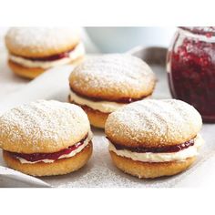 three pastries sitting on top of a white tray next to a jar of jelly