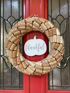 a wreath made out of wine corks with the word grateful written on it in front of a red door