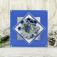 a blue and white card with a snowflake design on the front, surrounded by pine cones