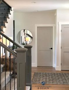 an entry way with stairs and a round mirror on the wall next to a door