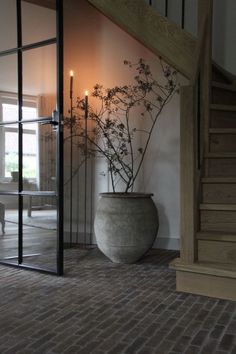 a vase with some flowers in it sitting on the floor next to a stair case