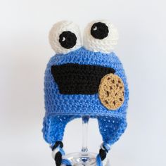 a crocheted blue hat with googly eyes and a cookie on the front