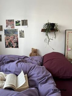 an unmade bed with purple sheets and a teddy bear on the pillow in front of it