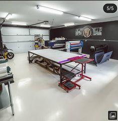 a garage with several different types of tools on the table and two motorcycles in the background