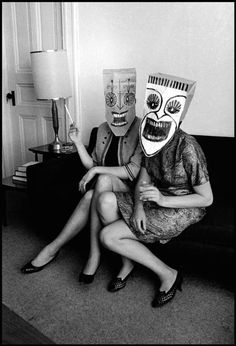 two people wearing masks sitting on a couch