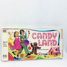 an old game called candy land is shown in the box with its cover open and two children's toys behind it