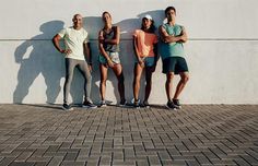 four people standing in front of a white wall